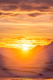 A breathtaking view of a vibrant winter sunset illuminating snow-covered mountains in Iceland. The