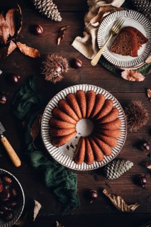 A delicious chestnut cake sits elegantly on a rustic table, surrounded by autumn leaves and pine