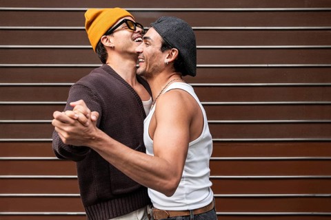 A joyful couple dances and smiles, capturing a moment of happiness and love. They wear casual