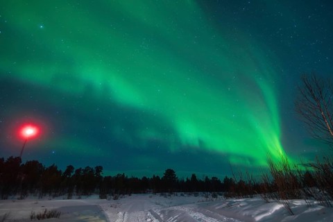 Captivating view of the Aurora Borealis shimmering above a snow-clad landscape near Kiruna, Sweden,