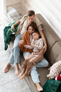 Top view image of a family of four celebrates Christmas in a warm, cozy setting. The mother,