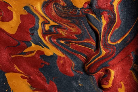 Vibrant swirls of metallic red, gold, and black paints merge, forming a captivating abstract
