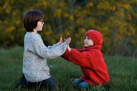 A boy and a girl enjoying a playful moment together in a vibrant autumn park setting, surrounded by