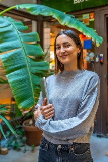 Vertical portrait of a beauty young female entrepreneur standing outside a coworking office holding