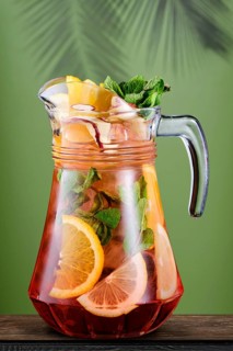 Pitcher with cold citrus sangria over green background