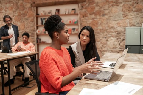 A diverse group of professionals engages in discussion within a modern coworking space,