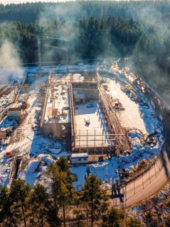 Snow-covered construction site with scaffolding and crane in the wintry forest, new fire station,