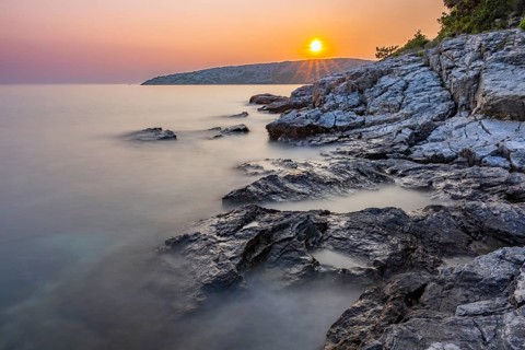 Sunset over crystal clear water on the beach of Ustrine Bay on the island of Cres, long exposure,