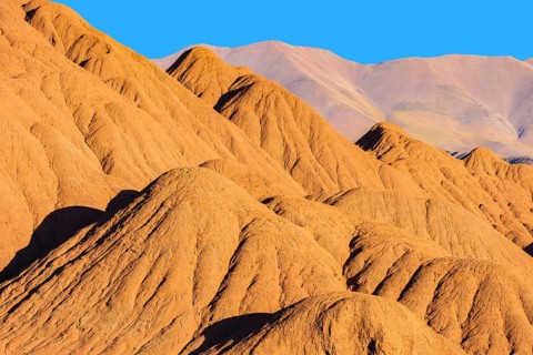 Rich orange and ochre hills of the Devil's Desert in Salta, Argentina, showcased against a clear