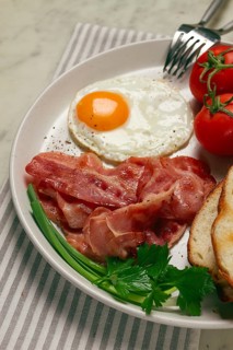 Breakfast, fried egg, bacon and bread, with cherry, on a light background, homemade, no people