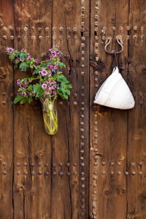 Rustic wooden door with a bouquet of flowers and antique door hook, Pollensa, Majorca, Balearic
