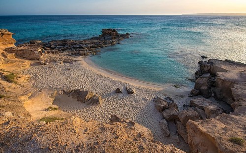 A tranquil beauty of Calo des Mort, Spain, featuring pristine sand and inviting turquoise waters,