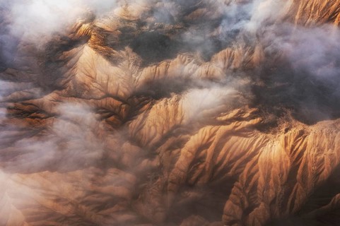 Captivating aerial view showcasing majestic mountain peaks partially enveloped in soft, swirling