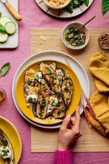Top view of cropped unrecognizable hand serving a beautifully garnished roasted courgettes served