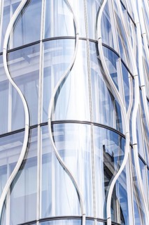 Stunning modern architecture showcasing a sleek, curved glass facade. The reflective surfaces and