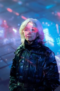 An elderly Asian woman wearing futuristic augmented reality glasses in a vibrant metaverse
