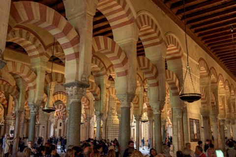 Architecture with striking arches and red and white stripes, interior filled with people, Cathedral