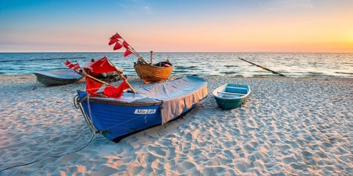 Fishing boats with red flags on fine sandy beach at sunrise, Baltic resort Kölpinsee, Usedom