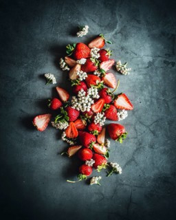 A visually striking arrangement of ripe strawberries beautifully scattered on a dark stone surface,