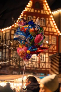 A colourful collection of balloons in front of traditional architecture at a lively Christmas
