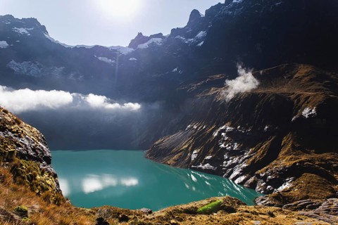 A stunning turquoise crater lake at El Altar volcano, Ecuador, surrounded by rugged peaks, golden