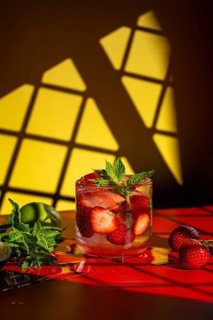 A refreshing strawberry mojito garnished with fresh mint and sliced strawberries in a clear glass.