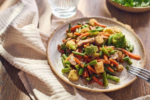 Plate of stir-fried mixed vegetables with green beans, carrots, baby corn, romanesco and mushrooms