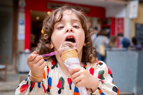 A young girl delights in a chocolate ice cream cone, savoring every bite on a sunny day in a