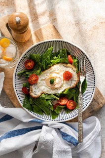 Top view of a fresh and nutritious lunch featuring crisp spinach leaves, juicy cherry tomatoes, and