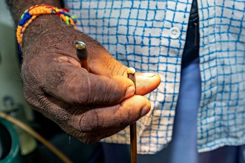 Close-up of a hand with a colored bracelet holding a small object, the gemstone cutters in the city