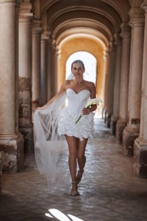 A bride in a stunning white gown gracefully walks down the aisle of the ancient villa in Treia,