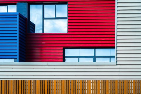 This image captures the vibrant and modern urban facade of a building, featuring a bold mix of red,