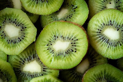 Top view of fresh kiwi slices displaying their vibrant green flesh and dark seeds. The close up