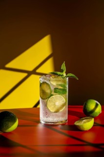 Vibrant image of a classic mojito, featuring fresh lime slices and mint leaves. Set against a bold
