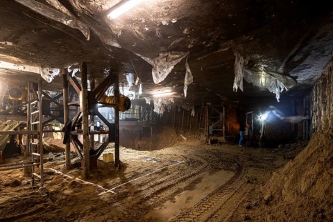 An expansive underground construction site featuring heavy machinery, scaffolding, and industrial