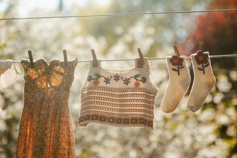 A vibrant scene of freshly washed clothes hanging on a clothesline, basking in warm sunlight. The
