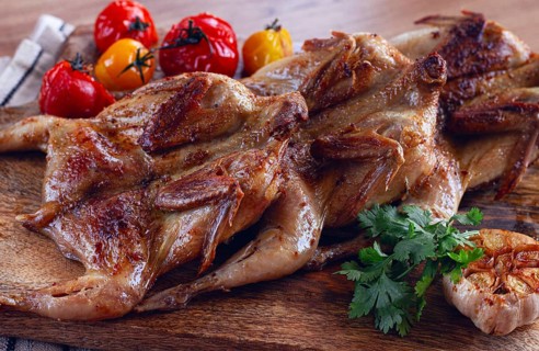 Grilled quail meat, on a wooden chopping board, tobacco, in the oven, with spices, homemade,