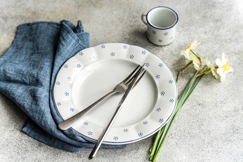 From above, a dining setup featuring a white plate with blue polka dots, accompanied by silverware