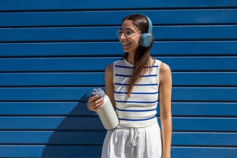 Smiling woman enjoying her active outdoor lifestyle in the city, wearing headphones and holding a