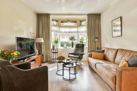 A beautifully arranged living room featuring comfortable furniture, a large window, plants, and