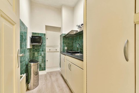A sleek, modern kitchen showcases minimalist design with green tiled walls, clean cabinetry, and