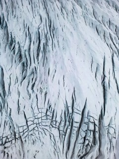Aerial view of the Icelandic winter terrain, showcasing a dramatic, snow-covered landscape with