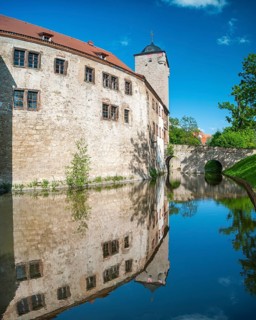 The moated castle of Kapellendorf is reflected in the water of the moat, Thuringia, Germany