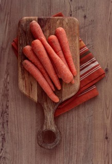 Fresh carrots on a chopping board, wooden table, raw carrots, no people