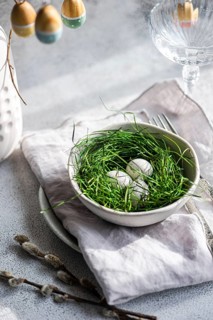 A fresh Easter setting featuring painted eggs tucked delicately within lush green grass, arranged