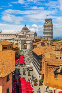 Above the rooftops of Pisa, behind the Cathedral of Santa Maria Assunta and the Leaning Tower, Via