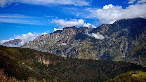Wide mountain landscape under blue sky surrounded by clouds, Stepantsminda, Caucasus, Georgia