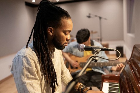 Two musicians immerse themselves in crafting music in a recording studio. One plays the piano while