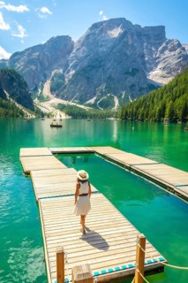 Woman enjoying a sunny summer day at lake braies, with the stunning seekofel mountain rising
