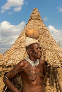 Woman with scar tattoo on her upper body carrying a calabash drinking bowl on her head, ethnic